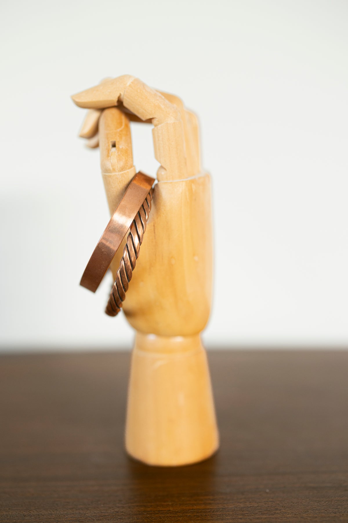 Kopero Premium Pulseras de Cobre Trenzada y Lisa, vista lateral sobre mano de joyería de madera