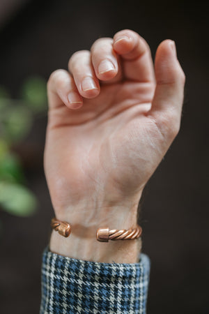 Pulsera de cobre Kopero Trenzado, en la muñeca, con los extremos del alambre trenzado visibles