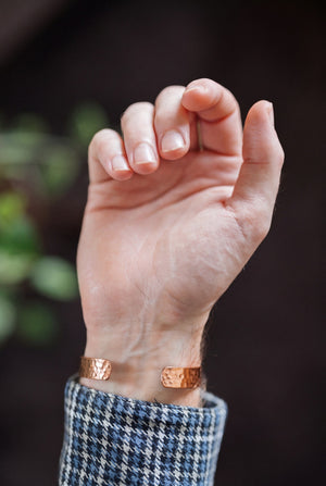 Pulsera de cobre Kopero Martillado, en la muñeca, con la mano abierta y los extremos de la pulsera visibles