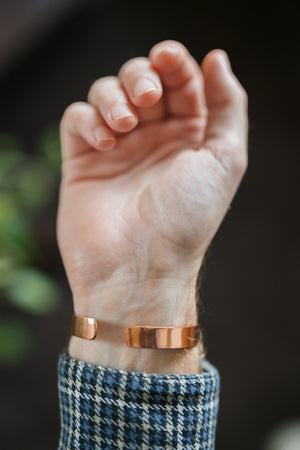 Pulsera de cobre Kopero Liso, en la muñeca, con la mano abierta y los extremos de la pulsera visibles
