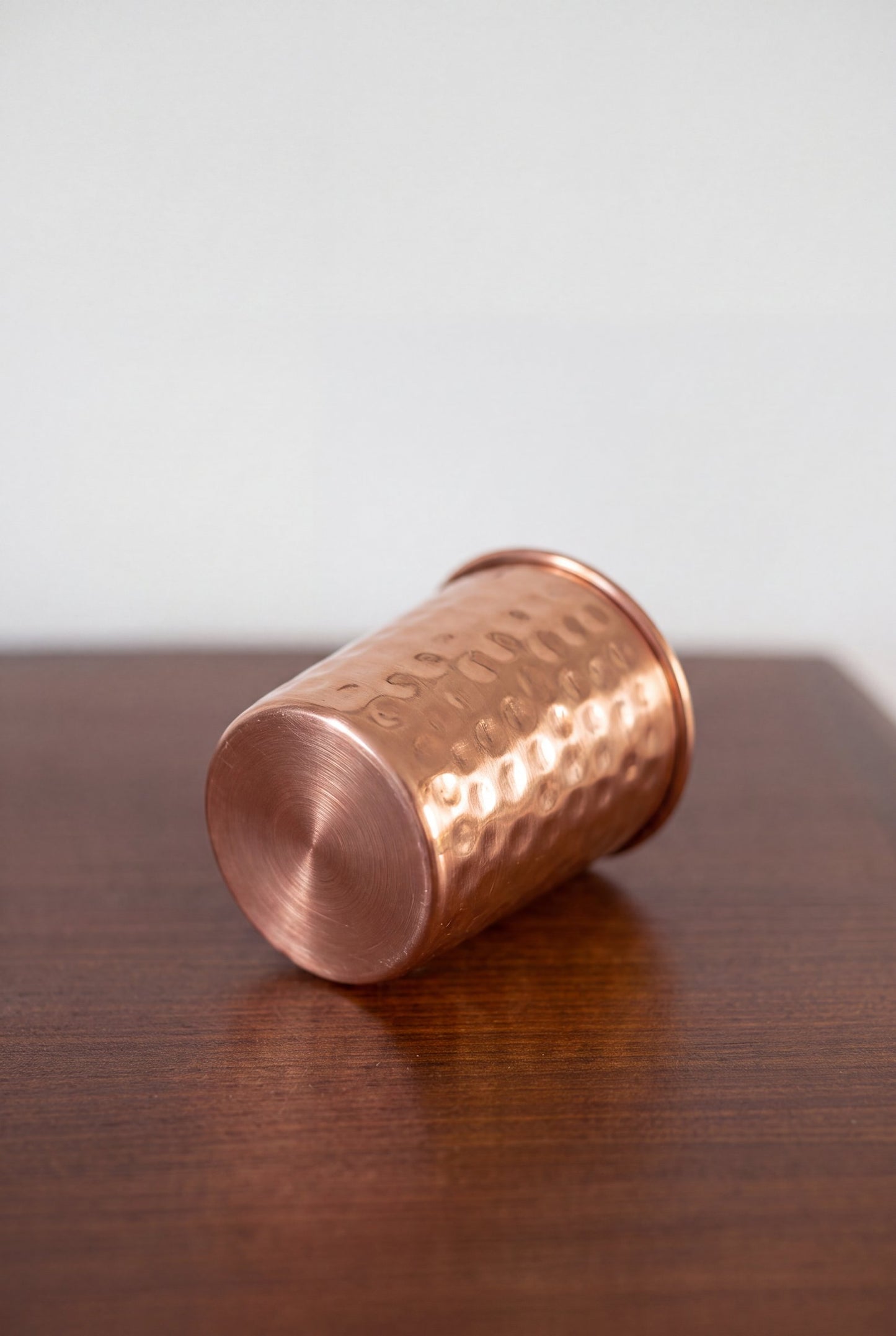 Vaso de Cobre Kopero Martillado tumbado sobre una mesa de madera