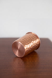 Vaso de Cobre Kopero Martillado tumbado sobre una mesa de madera