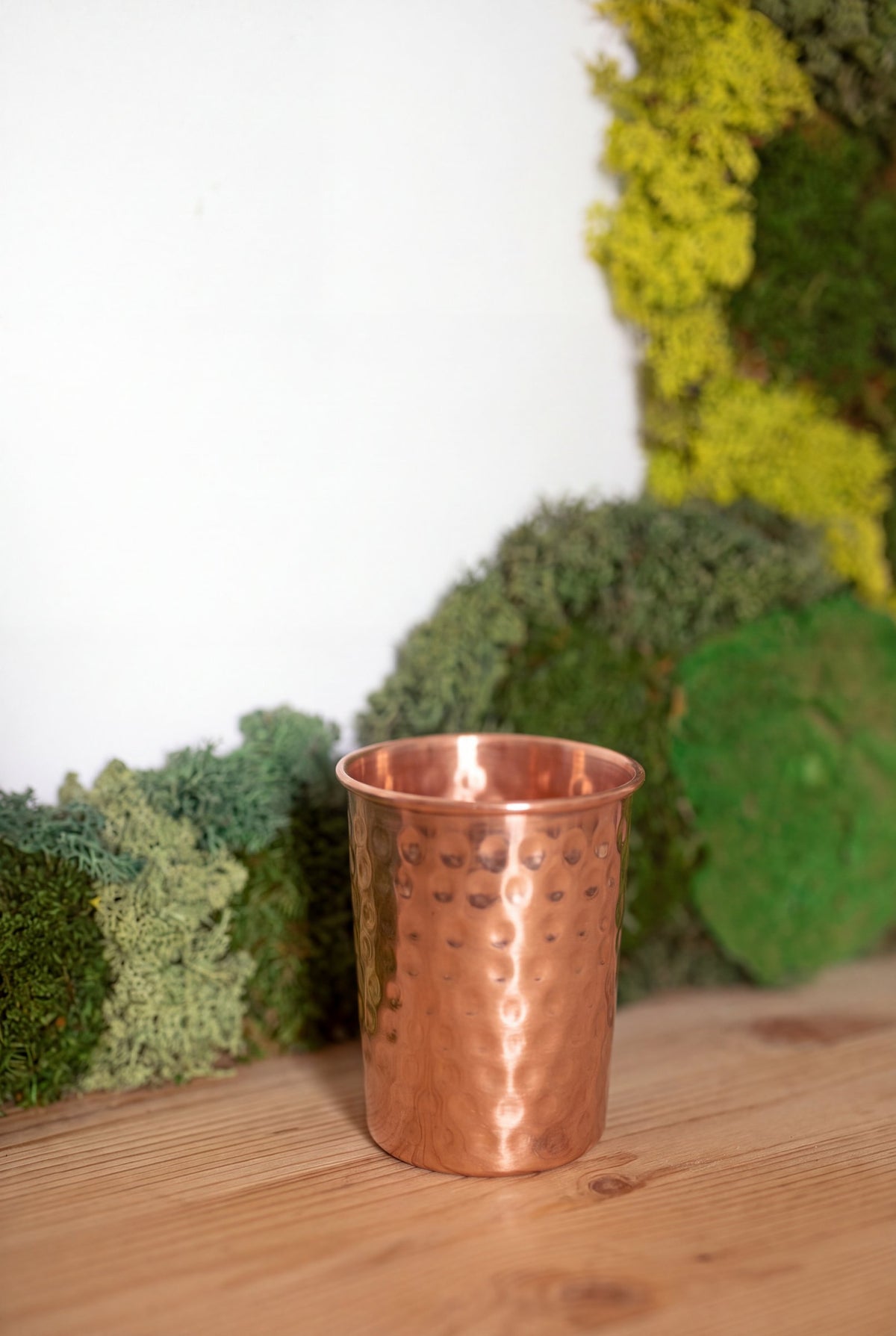 Vaso de Cobre Kopero Martillado frente a un cuadro de musgo sobre una tabla de pino