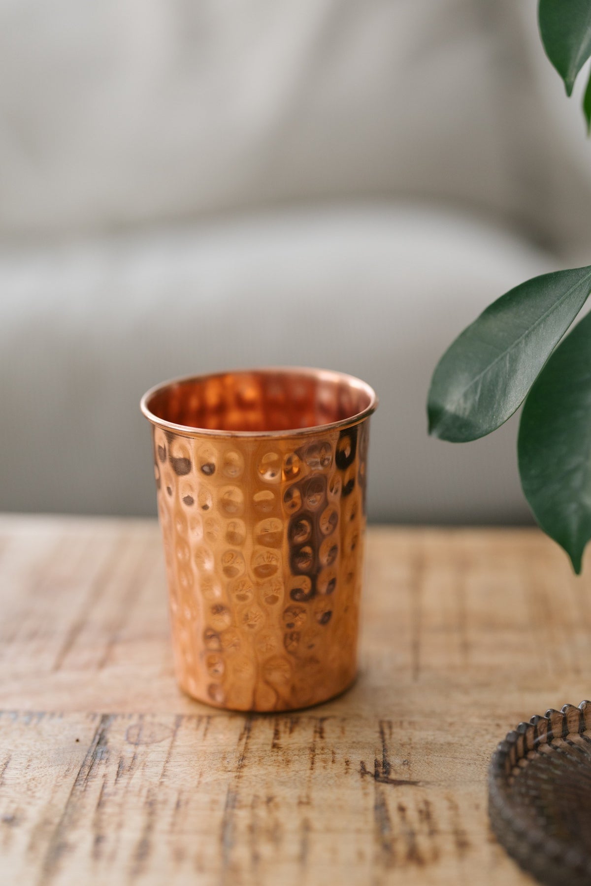 Vaso de cobre Kopero Martillado, sobre una mesa de madera frente a un sofá