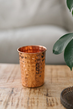 Vaso de cobre Kopero Martillado, sobre una mesa de madera frente a un sofá