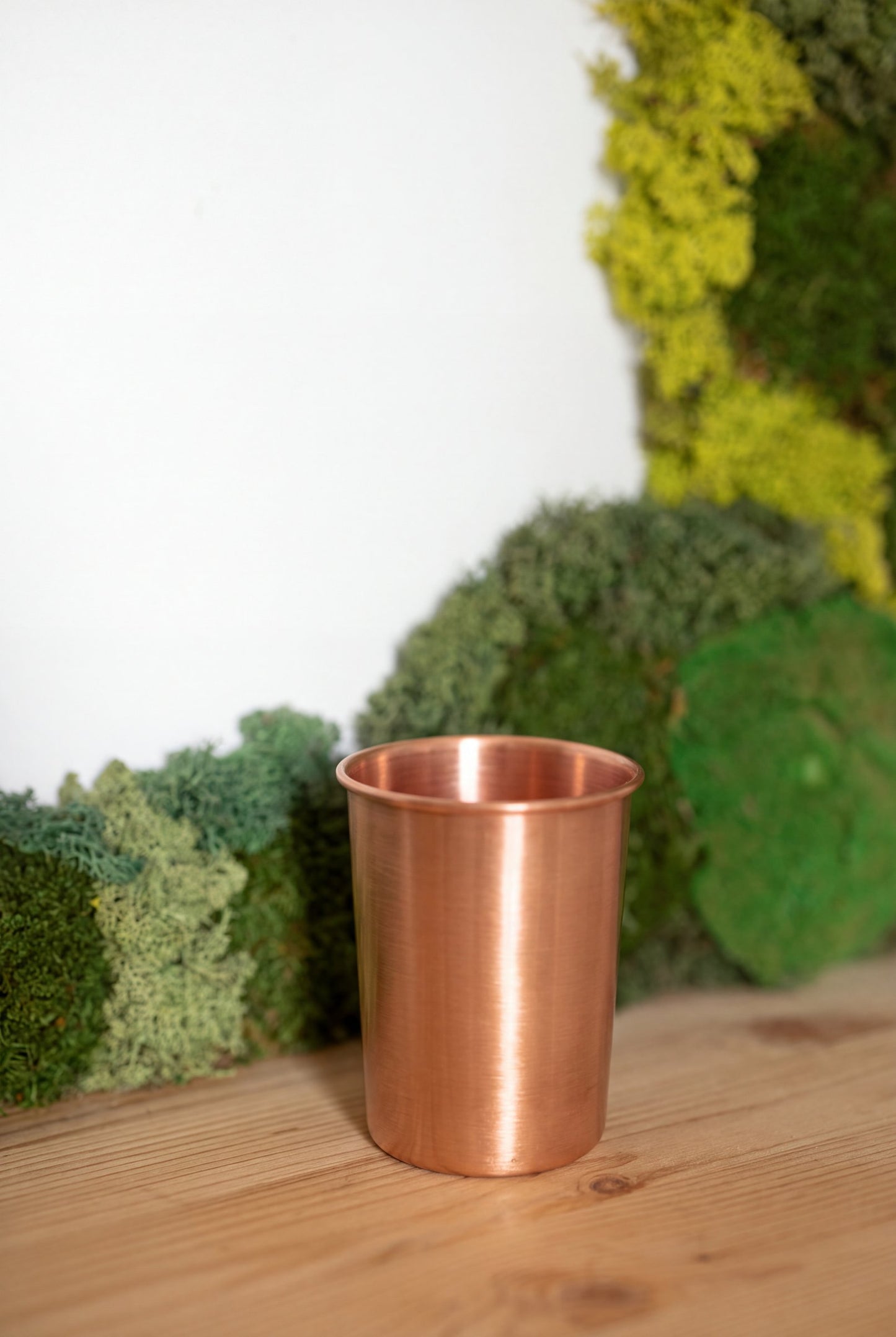 Vaso de Cobre Kopero Liso frente a un cuadro de musgo sobre una tabla de pino