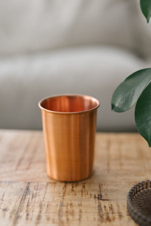 Vaso de cobre Kopero Liso, sobre una mesa de madera frente a un sofá