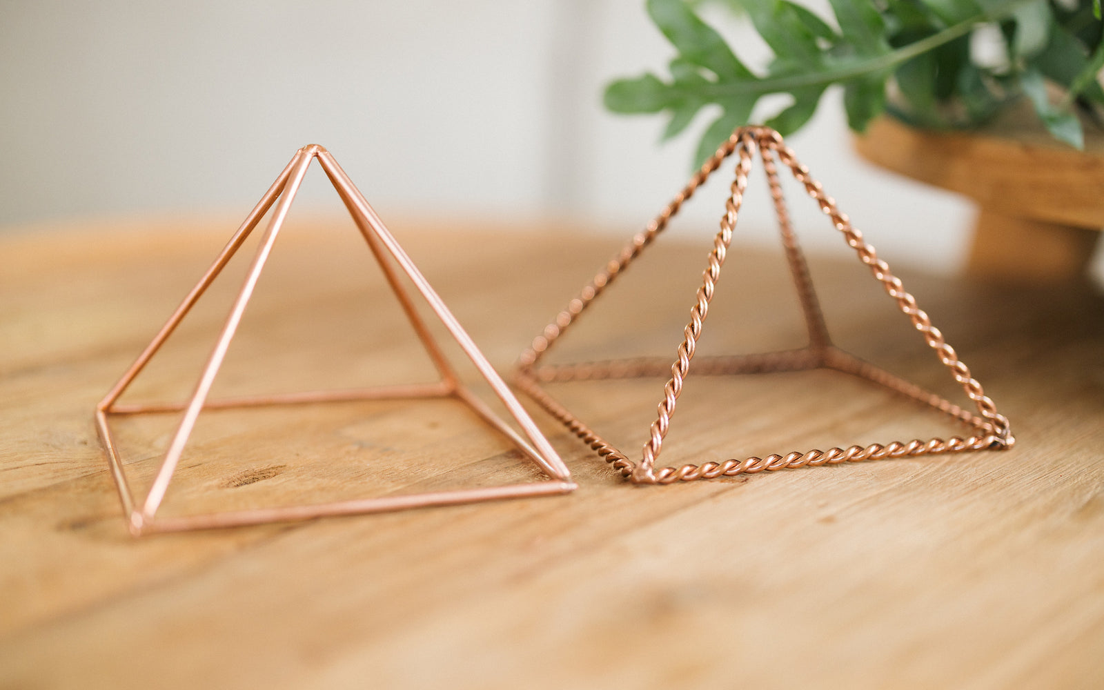 Dos pirámides de cobre, una trenzada y otra lisa, una junto a la otra sobre una mesa de madera