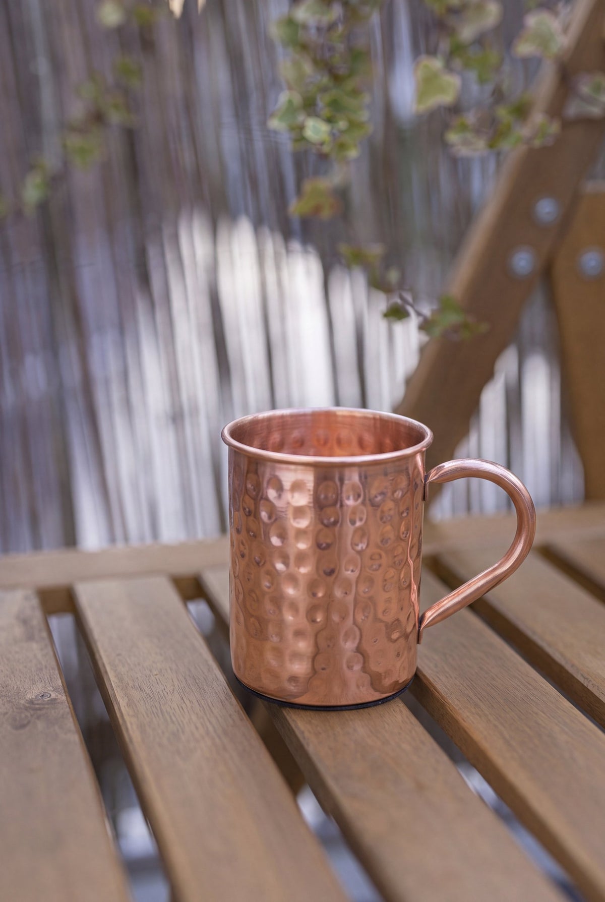 Taza de Cobre Kopero Martillada de 400 ml sobre un banco de jardín de madera