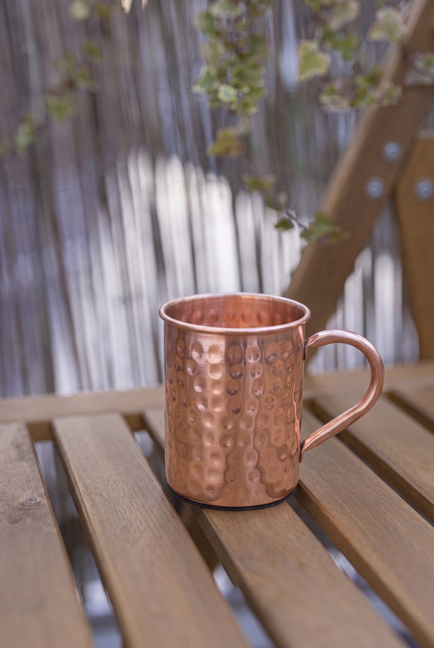 Taza de cobre Kopero Premium Martillada, 400 ml, 100% cobre puro, al aire libre sobre una mesa de jardín de madera