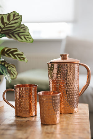 Taza de cobre Kopero Martillado, junto a un vaso y una jarra del mismo cobre