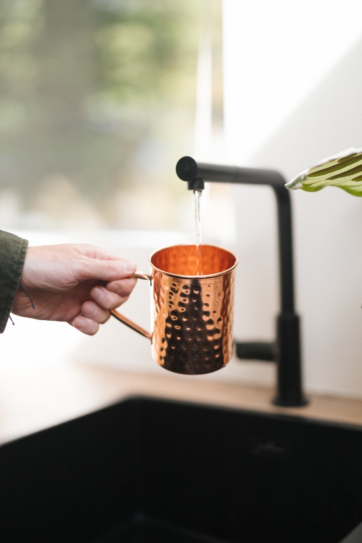 Taza de cobre Kopero Martillado, en una mano bajo el grifo