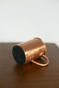 Taza de cobre Kopero Premium Lisa tumbada, con la base de fieltro visible