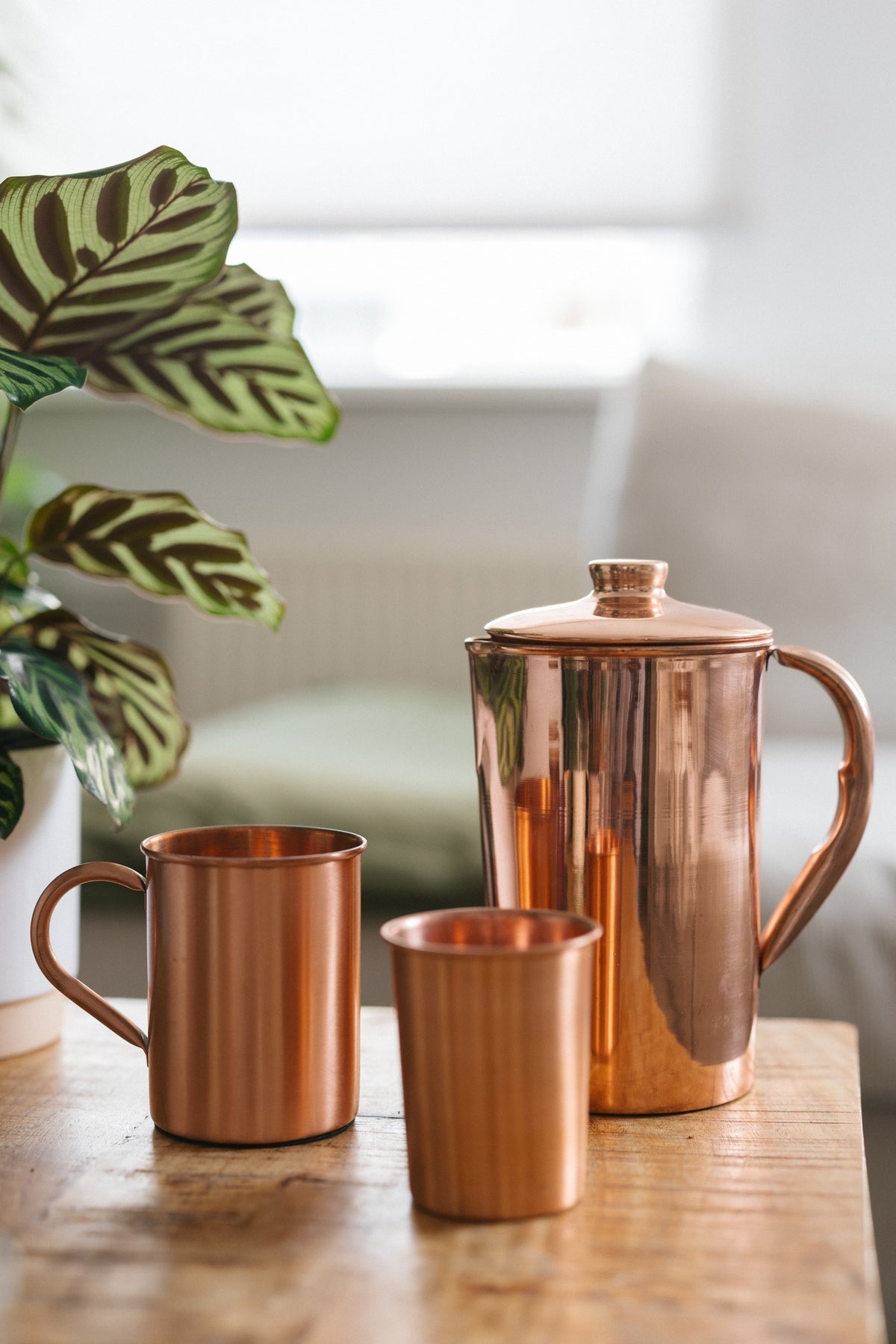 Taza de cobre Kopero Liso, junto a un vaso y una jarra del mismo cobre