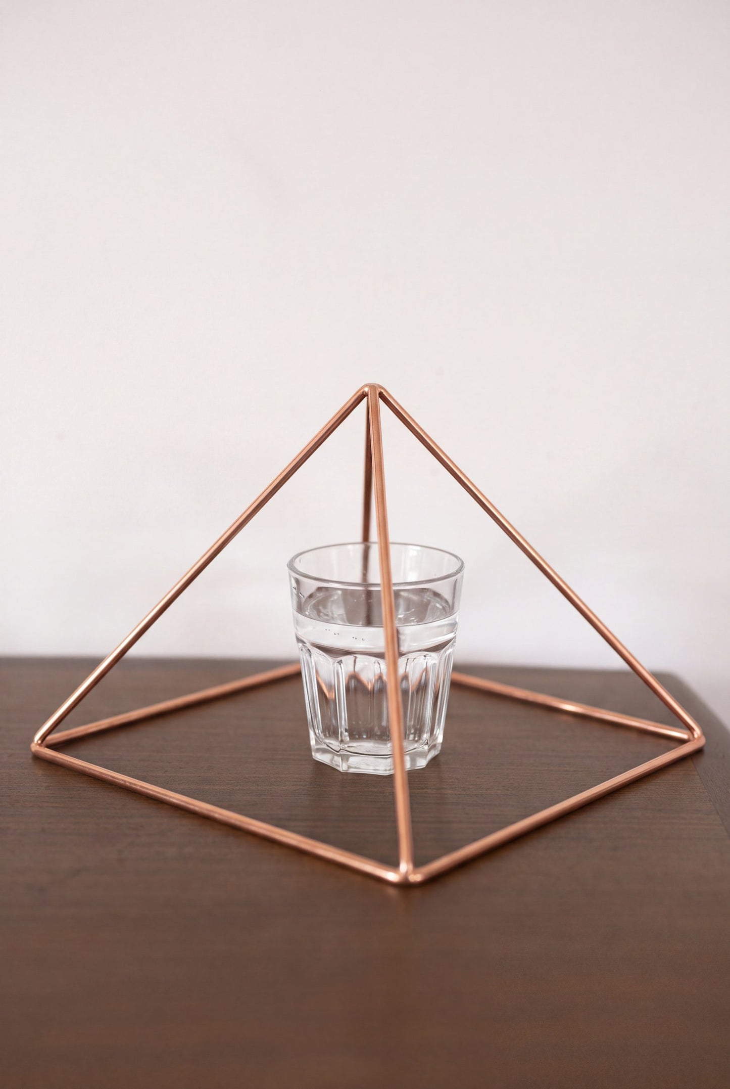 Pirámide Energizante de Cobre Kopero Lisa Grande (23,56 cm) sobre un vaso de agua