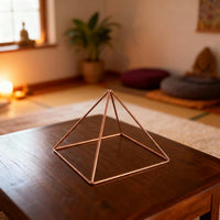 Pirámide Energizante de Cobre Kopero Lisa Pequeña (14,56 cm) sobre una mesa de centro en una sala de meditación