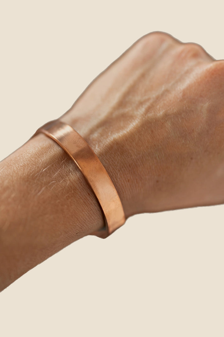 Pulsera de cobre Kopero Liso, en la muñeca, foto de producto sobre fondo blanco