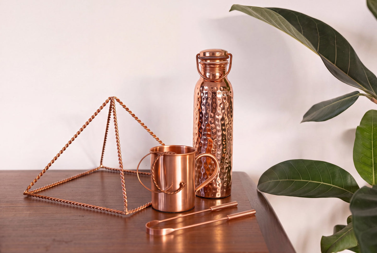 Raspador Lingual de Cobre Kopero junto a la pirámide de cobre, la taza y la botella de agua de la colección Kopero
