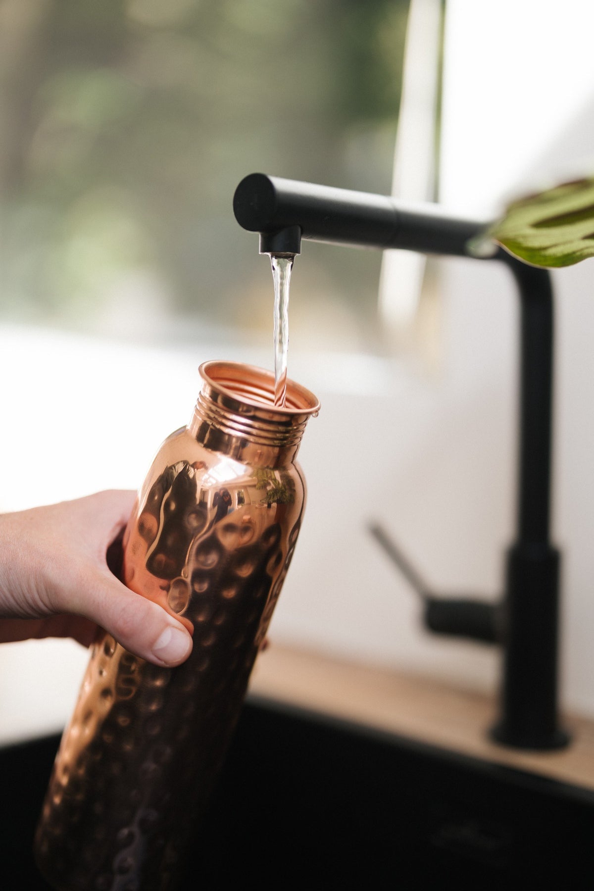 Botella de agua de cobre Kopero Martillado, bajo el grifo, mientras entra el agua