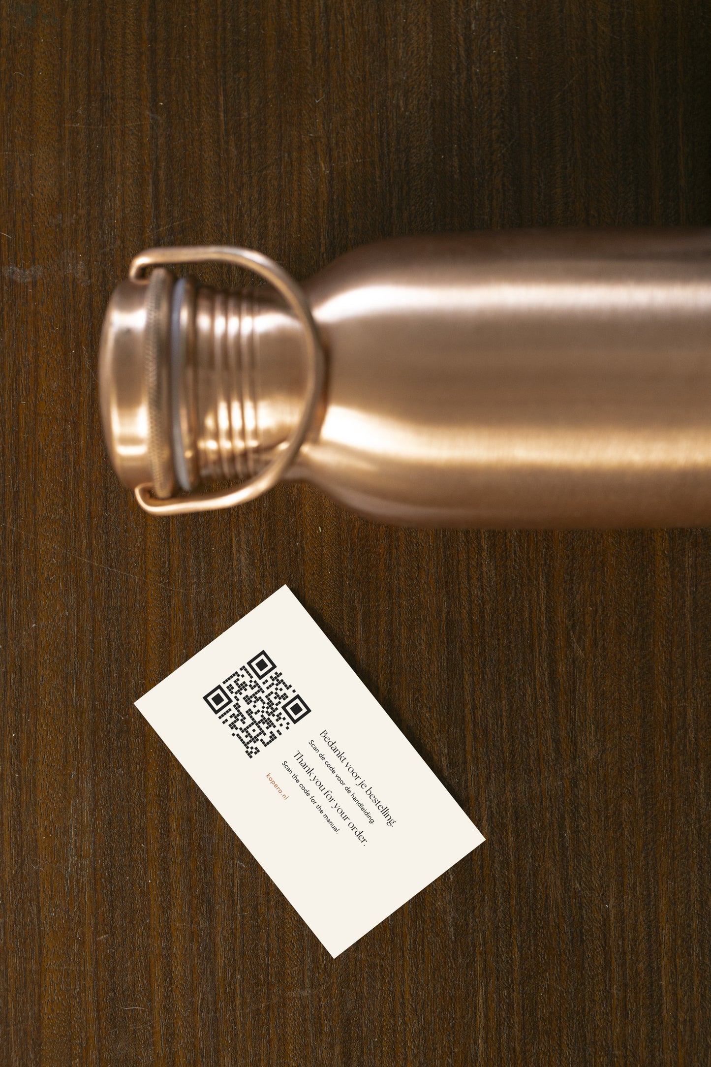 Botella de agua de cobre Kopero Lisa vista desde arriba con tarjeta de agradecimiento y código QR para el manual